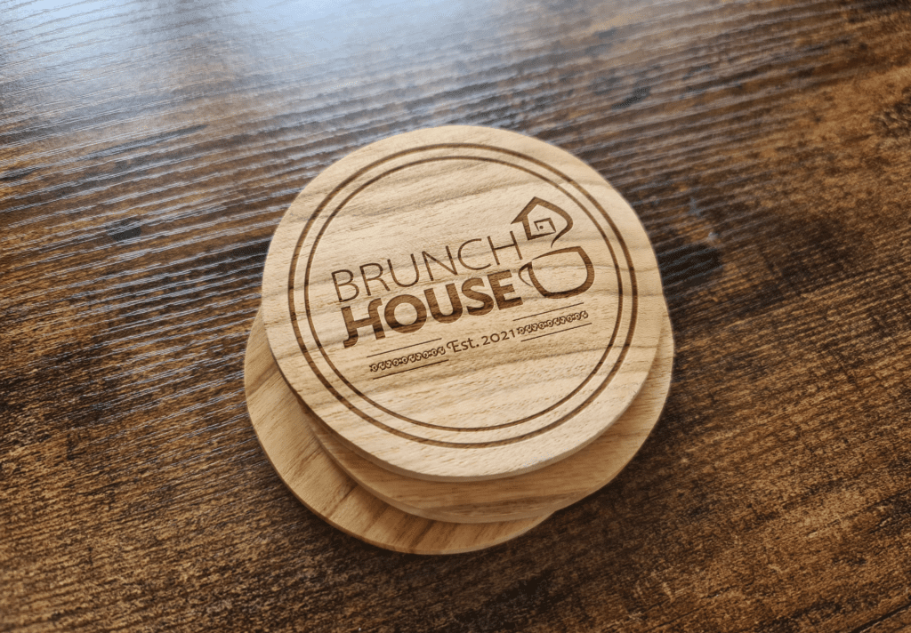 Wooden coasters with the name Brunch House burned into them.